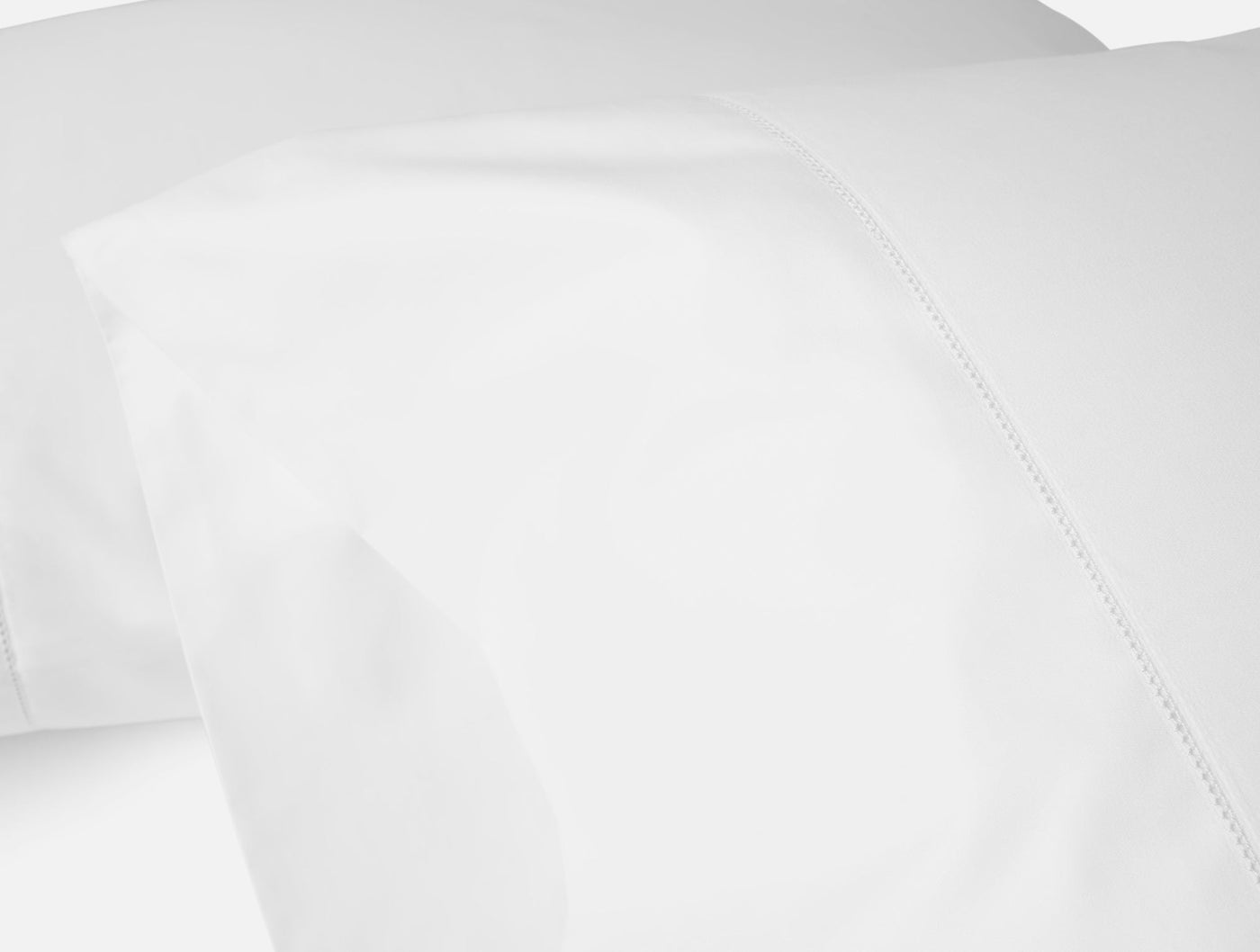 Close-up of white sateen sheet hem with delicate embroidered detail.