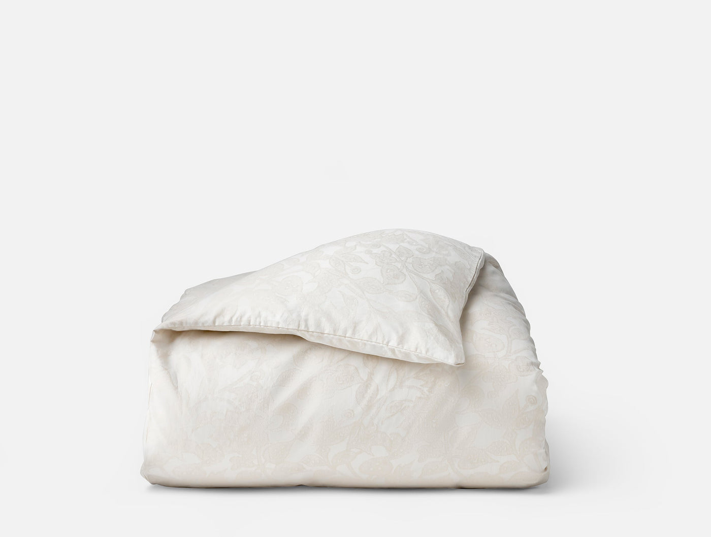 Coyuchi Heritage Percale Jacquard duvet cover folded, ivory with tone-on-tone floral pattern.