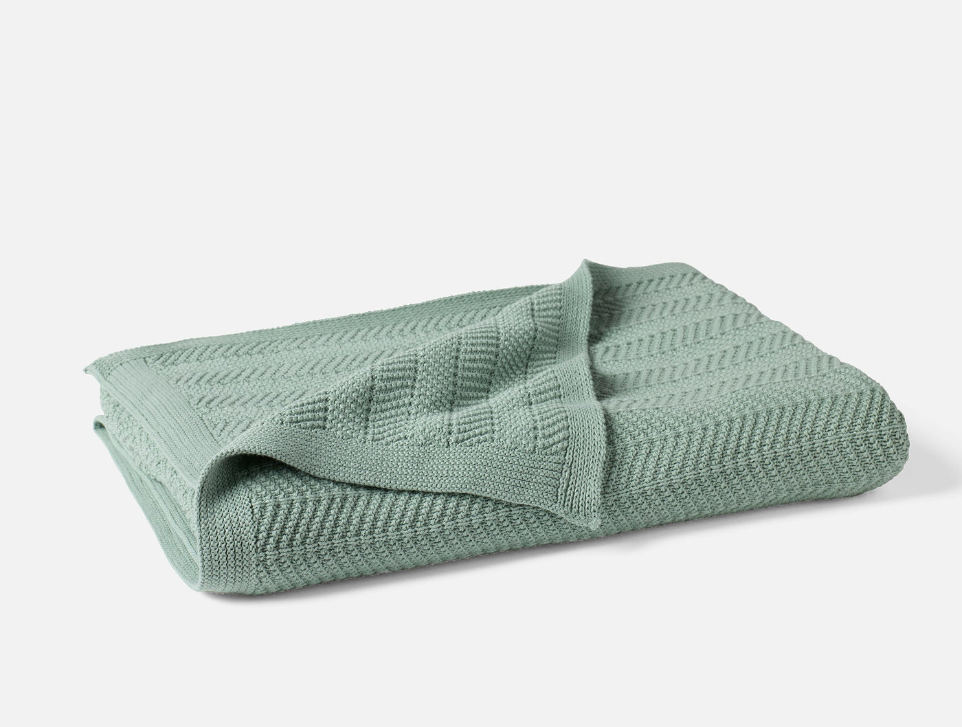 Coyuchi Hermosa Knit Throw folded, showing chevron knit texture in sage green.