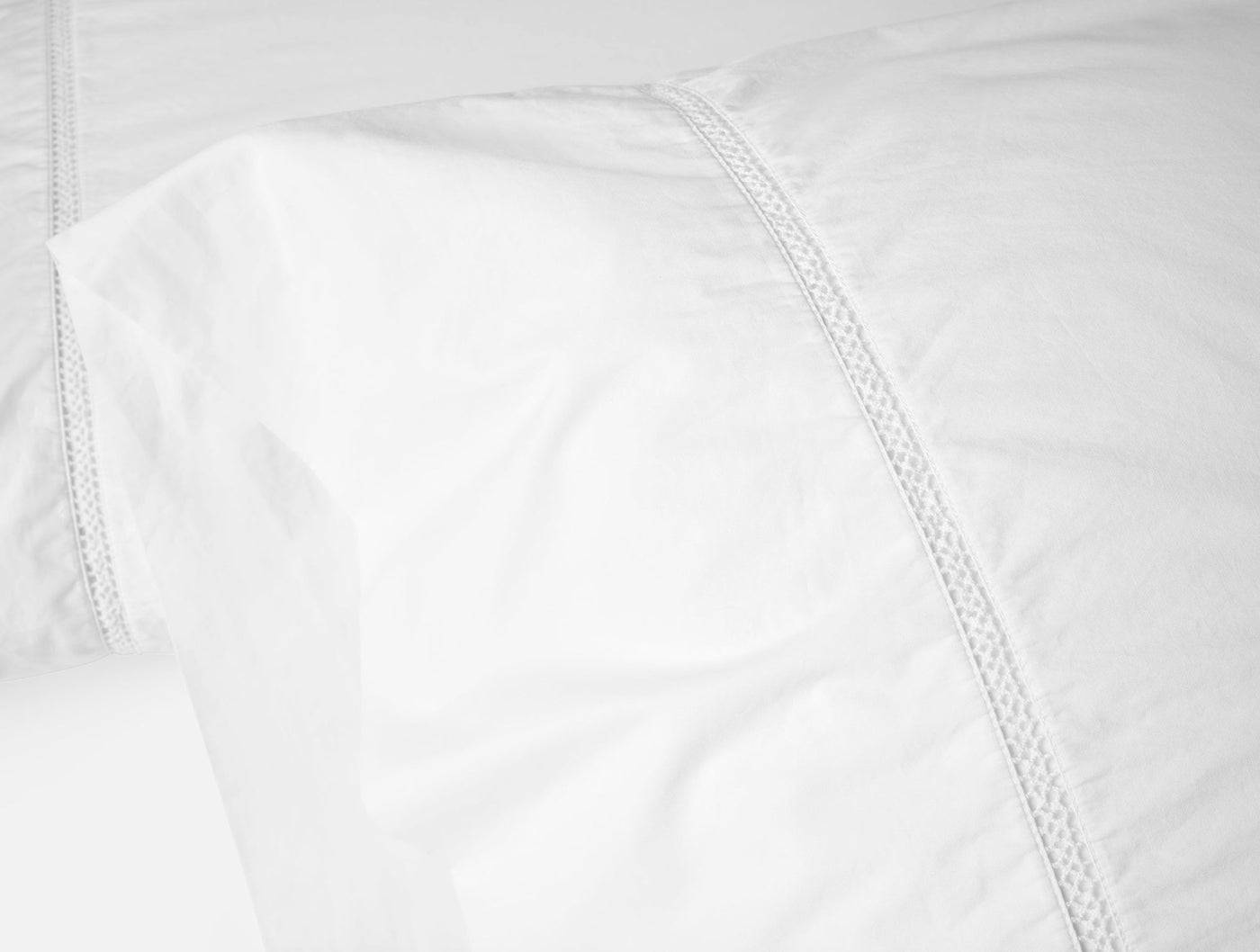 Close-up of white Coyuchi Lattice Percale pillowcase showing woven lattice trim detail.