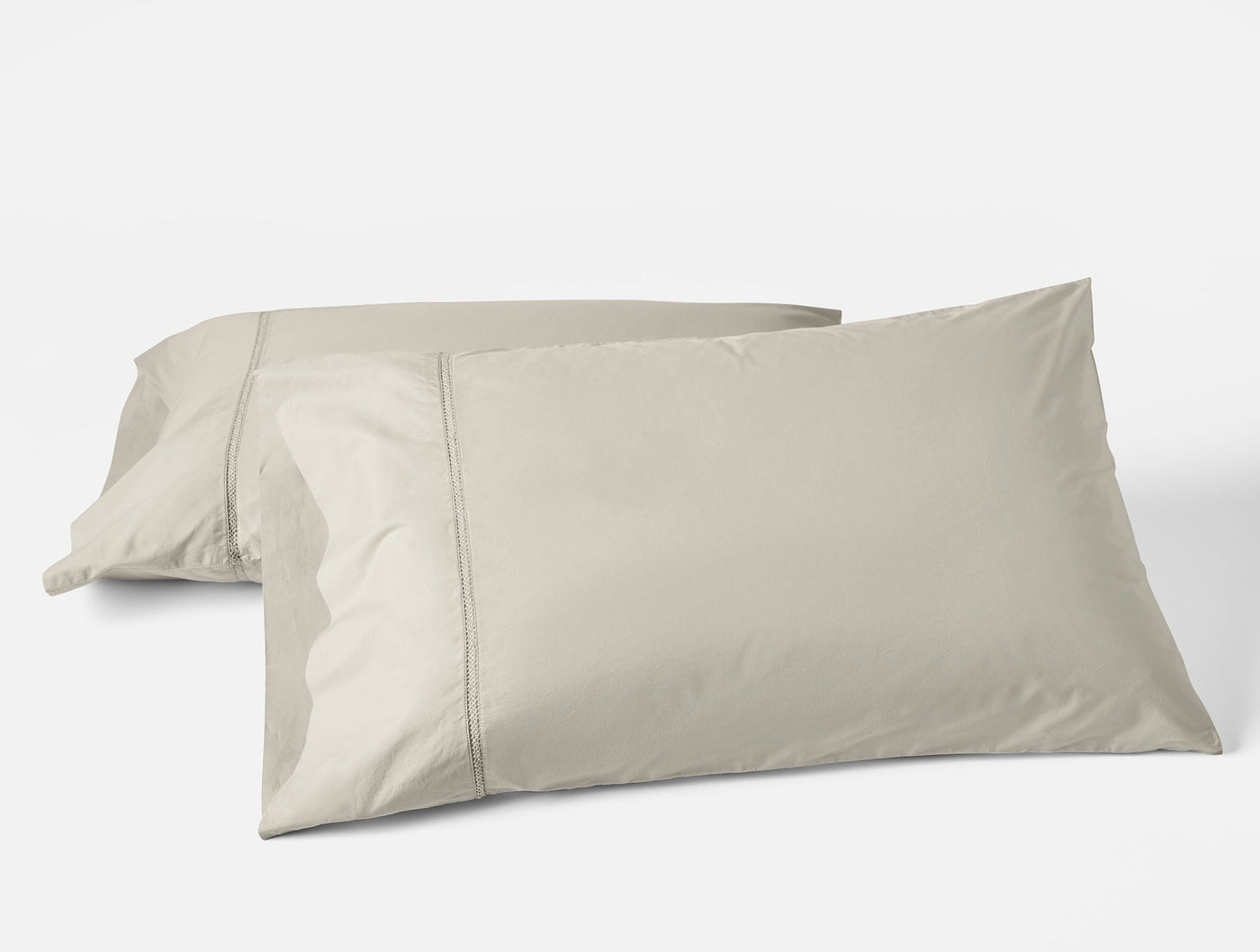 Two stone Coyuchi Lattice Percale pillowcases stacked, showing hemstitch detail.