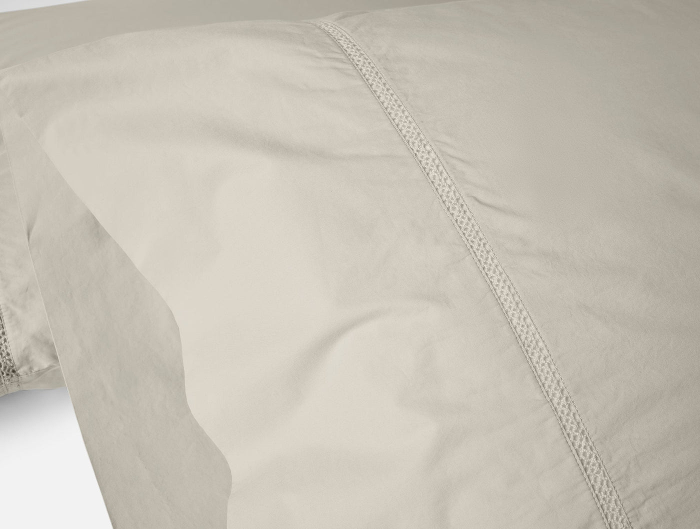 Close-up of Coyuchi Lattice Percale sheet set hem with intricate lace trim detail in warm linen.