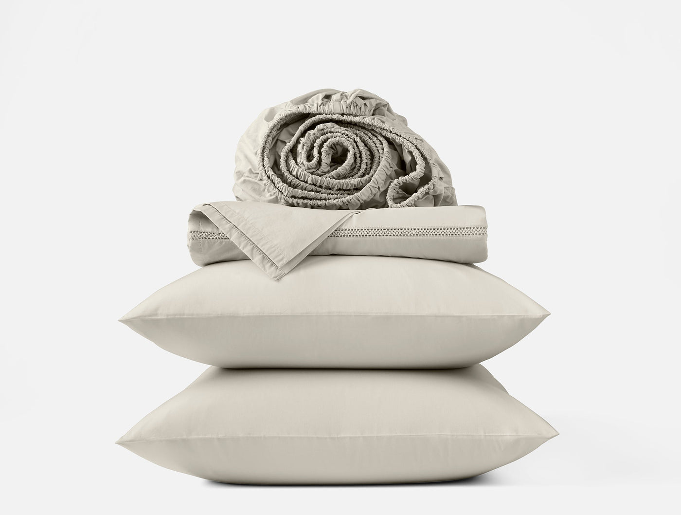Stacked ivory percale pillowcases with folded flat sheet and rolled fitted sheet on top.