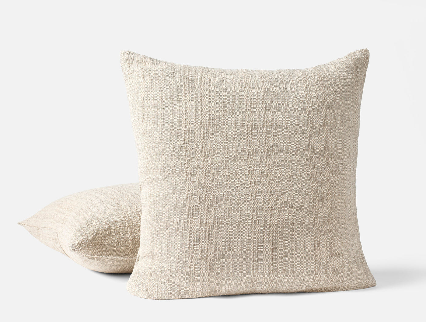 Pair of Coyuchi Lido ivory boucle-textured throw pillows, one upright, one flat.