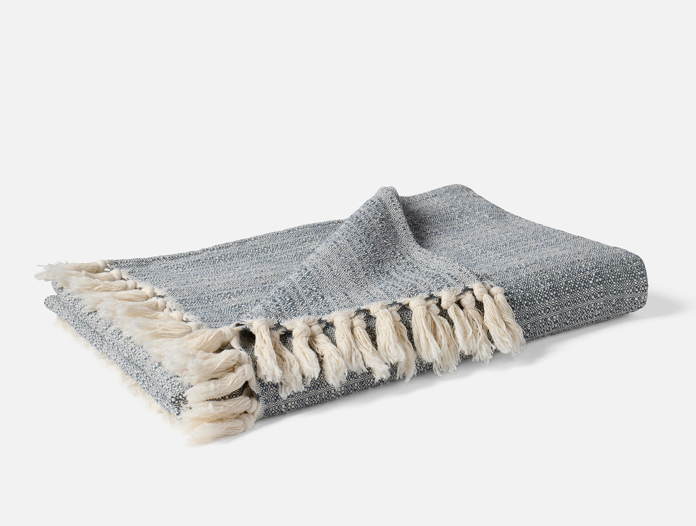 Close-up of Coyuchi Lido throw folded, showing slate woven texture and cream fringe detail.
