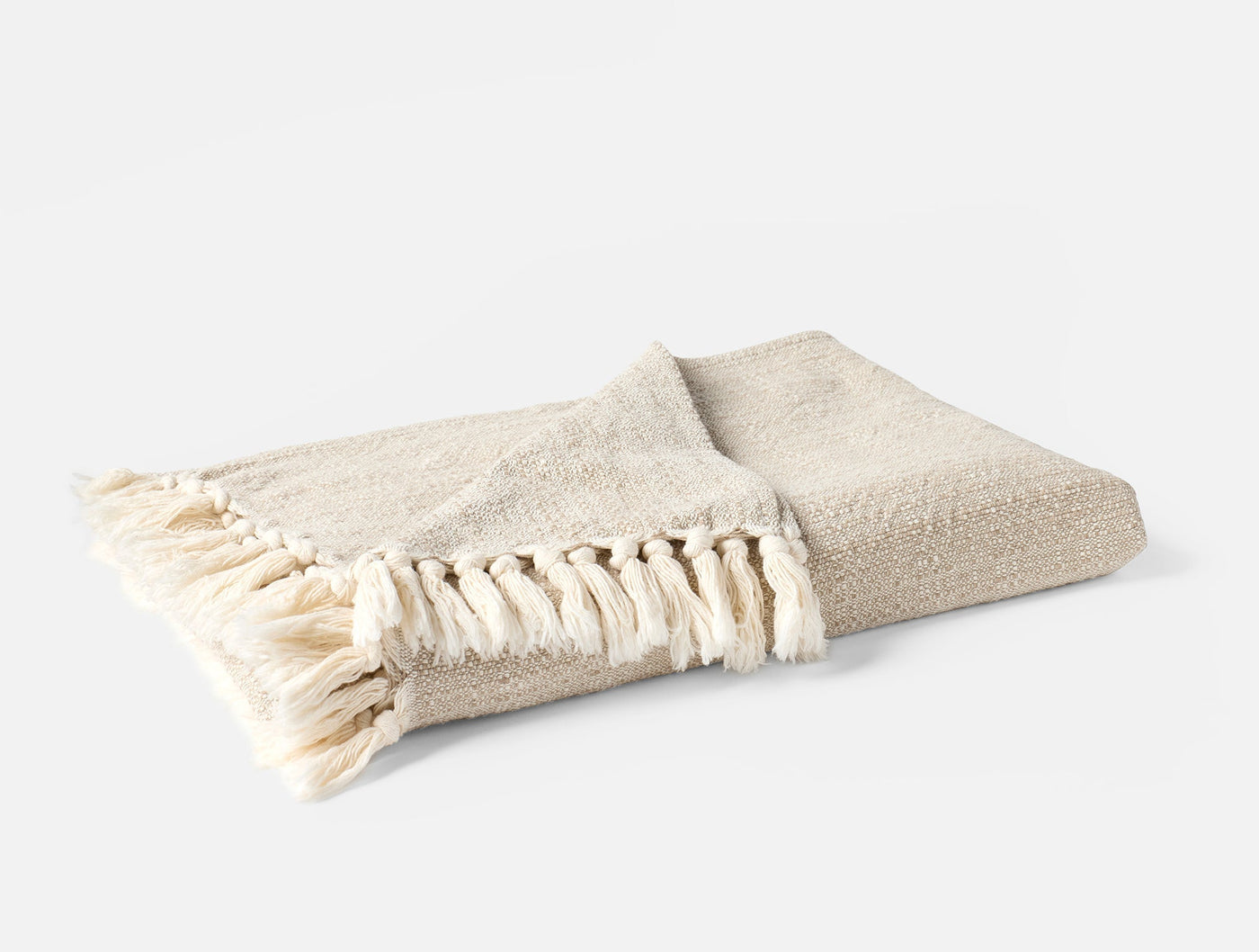 Folded ivory boucle throw with knotted fringe trim, side angle view.