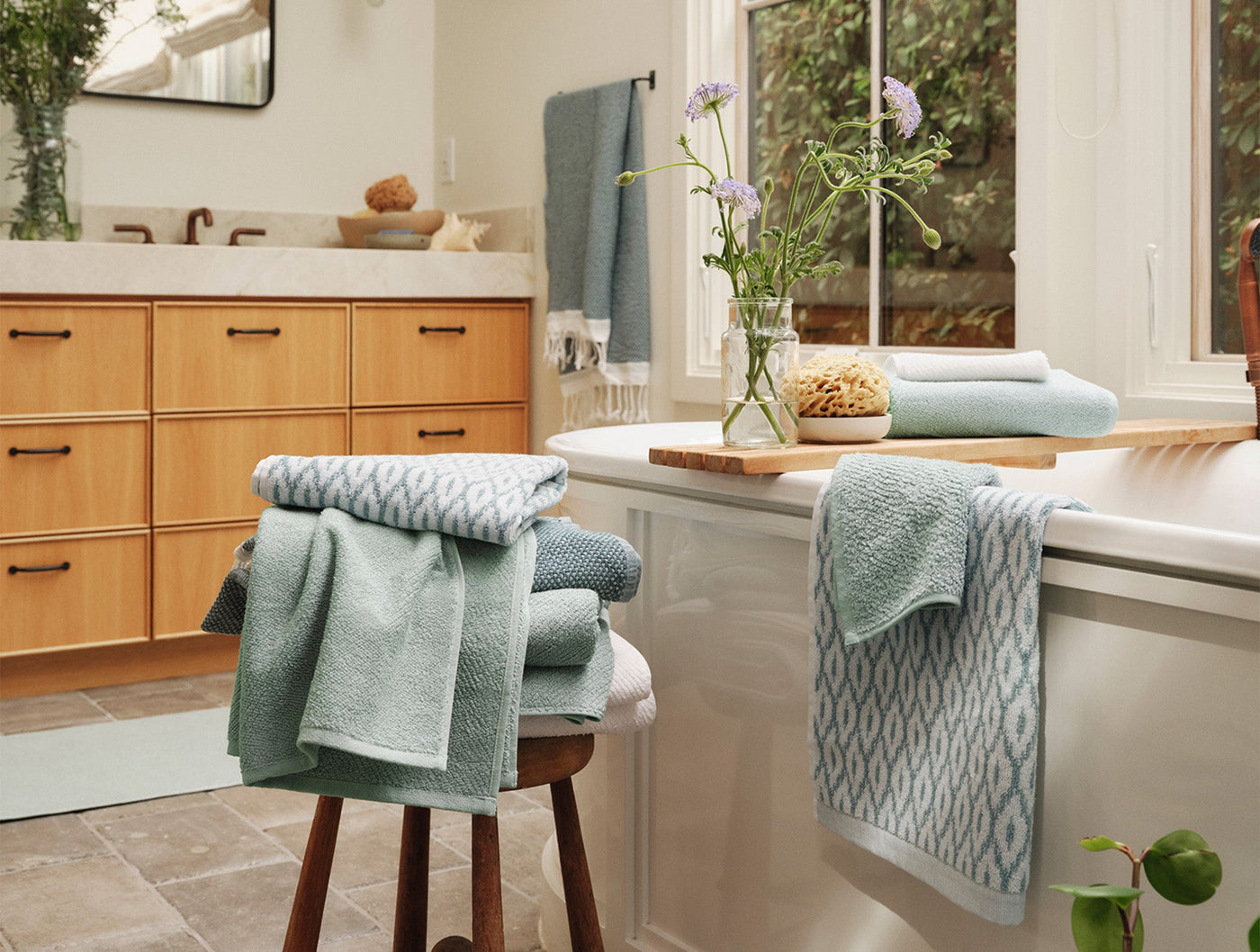 Coyuchi Air Weight wash cloths in sage and white geometric pattern styled in a bright bathroom.