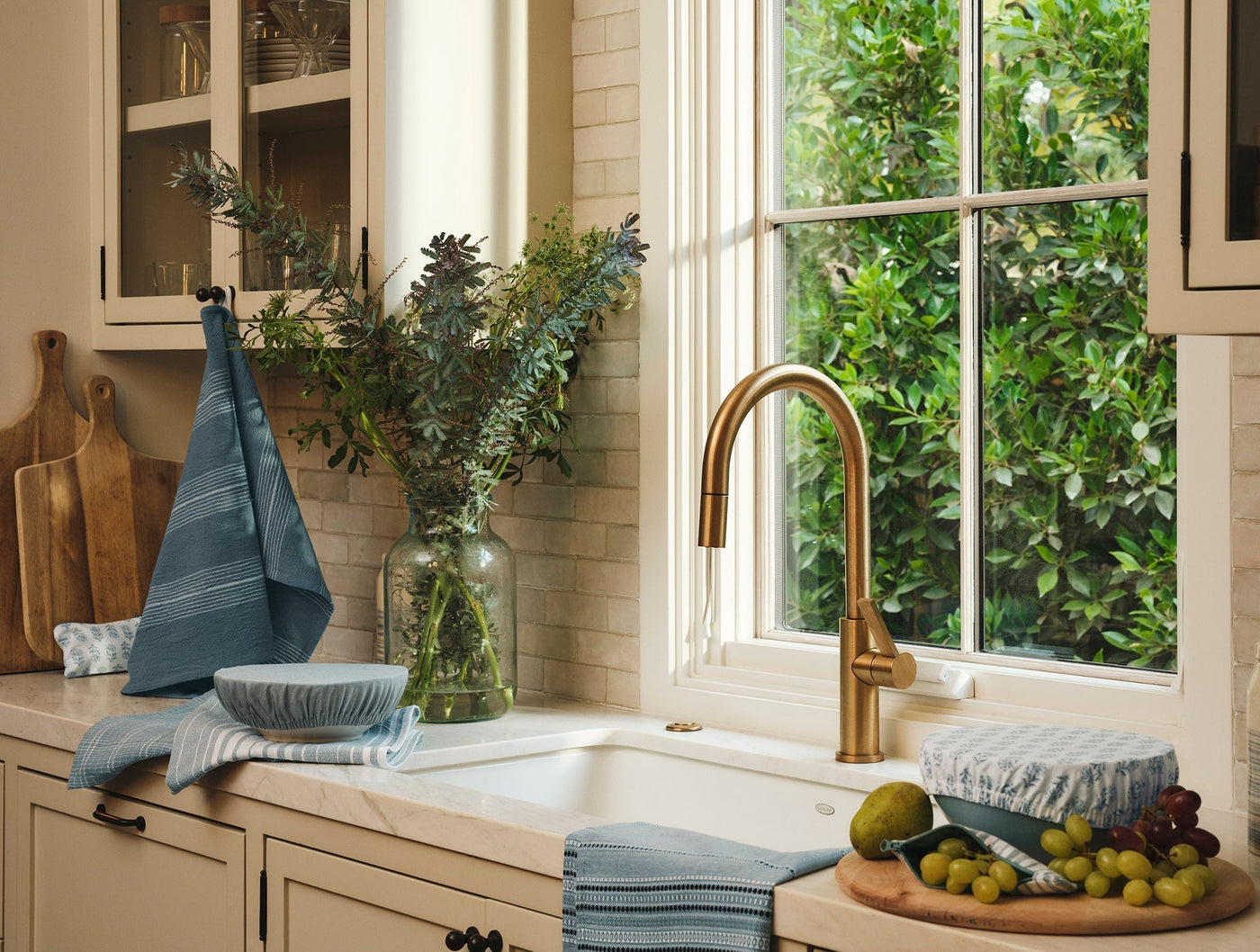 Coyuchi Fillmore kitchen towels in blue, draped and stacked beside a farmhouse sink.