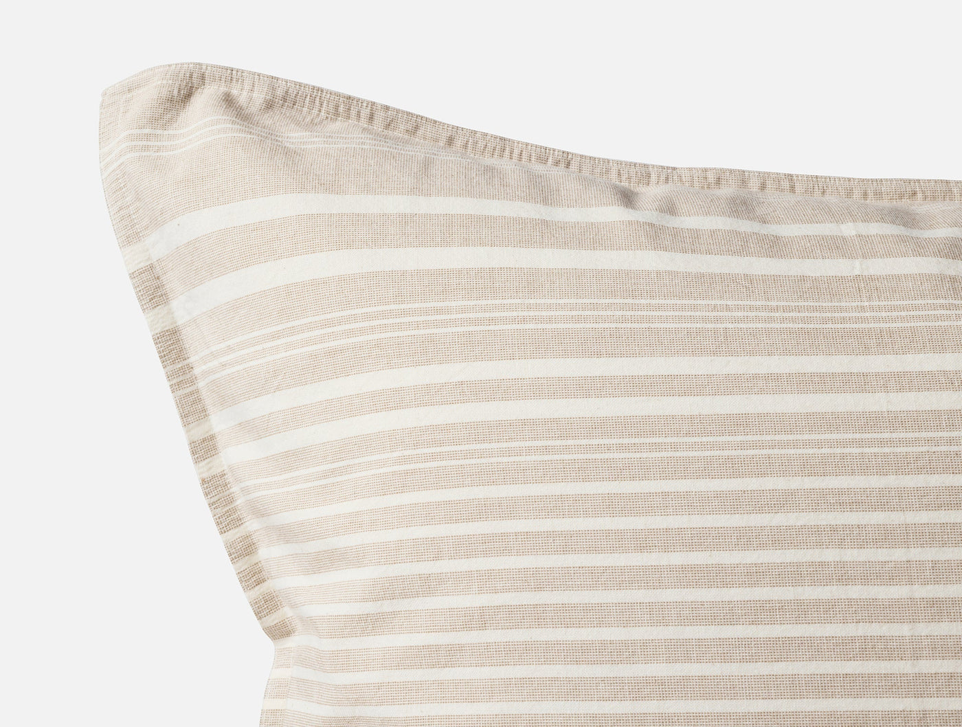 Close-up corner detail of a sand and white striped linen pillowcase with frayed trim.