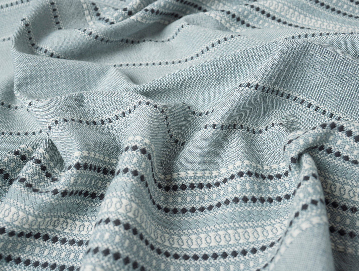 Close-up of Coyuchi Lobos napkin in sage, showing woven stripe and dotted pattern detail.