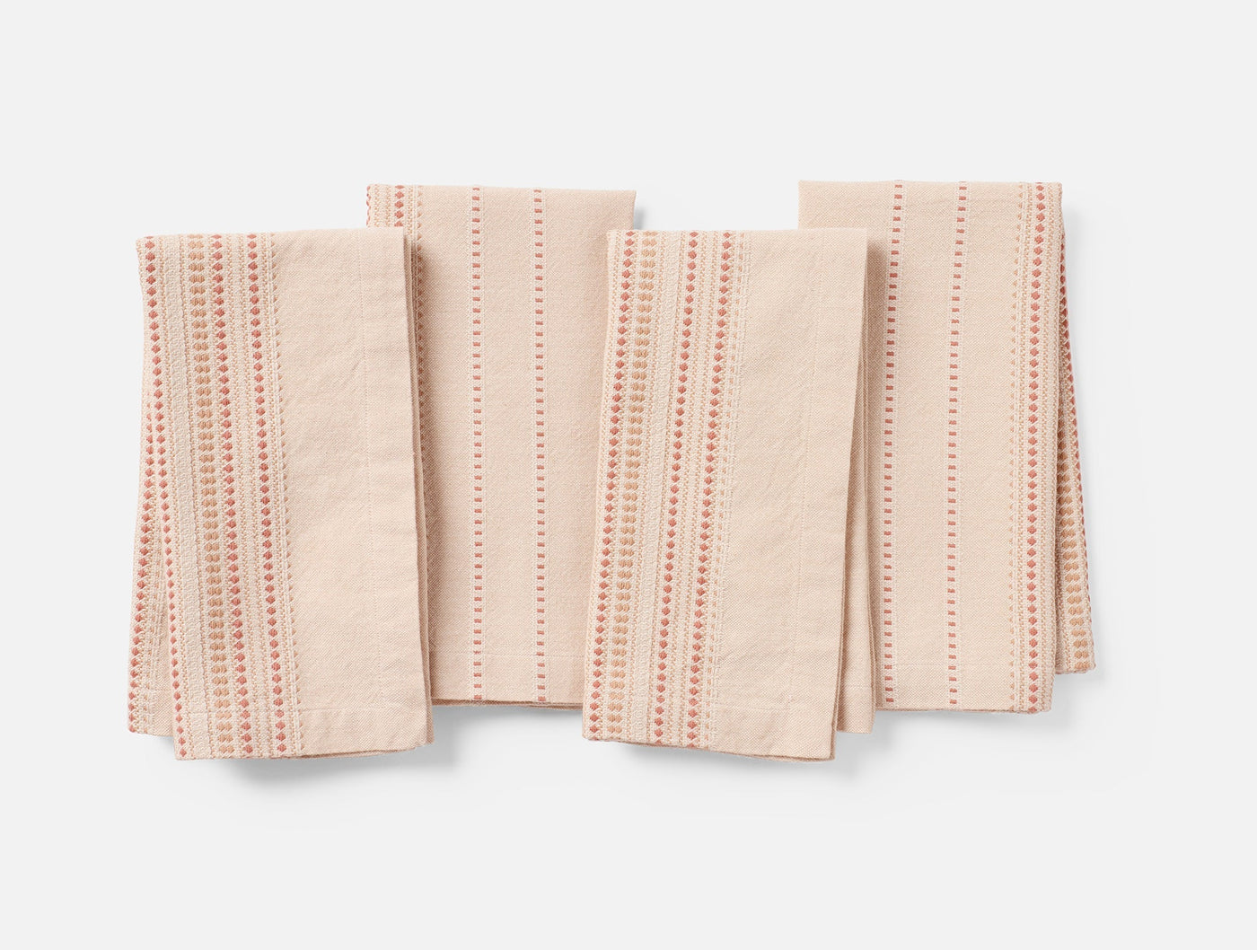 Coyuchi Lobos napkins in blush linen, set of four folded flat showing dotted coral stripe pattern.