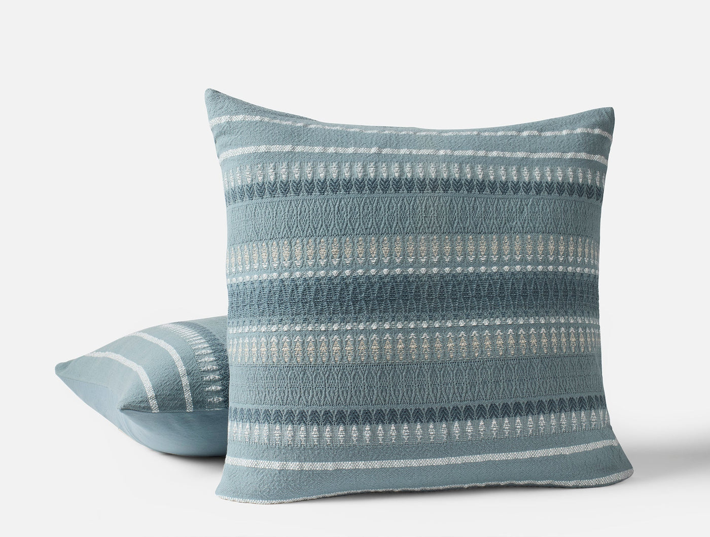 Coyuchi Lost Coast pillow in slate blue, showing front and back views with woven stripe detail.