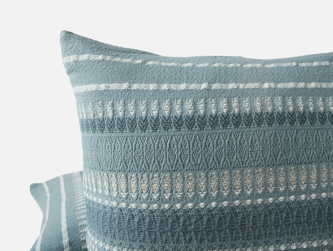 Close-up of Coyuchi Lost Coast pillow corner showing woven stripe and chevron detail in slate blue.