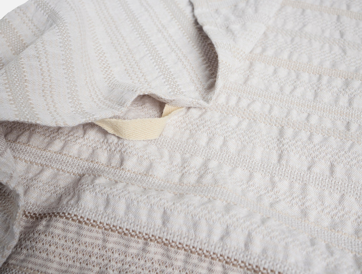 Close-up of Coyuchi Magnolia hand towel label and textured stripe weave detail in ivory.