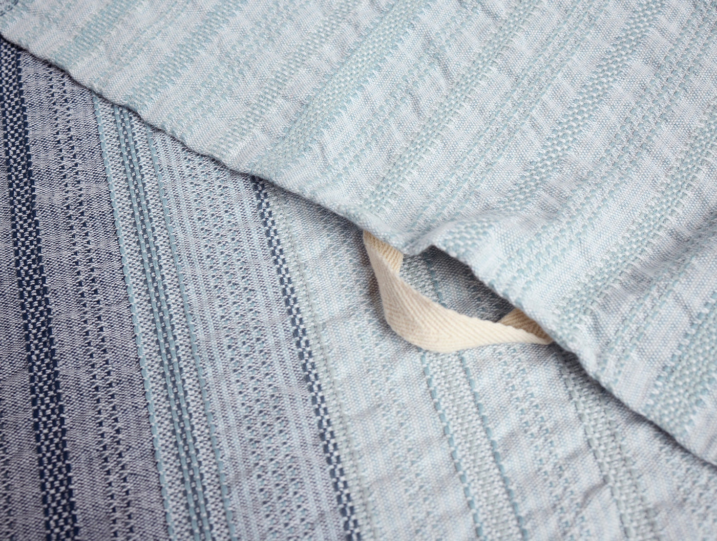 Close-up of Coyuchi Magnolia hand towel hem, showing woven stripe detail in mist blue.