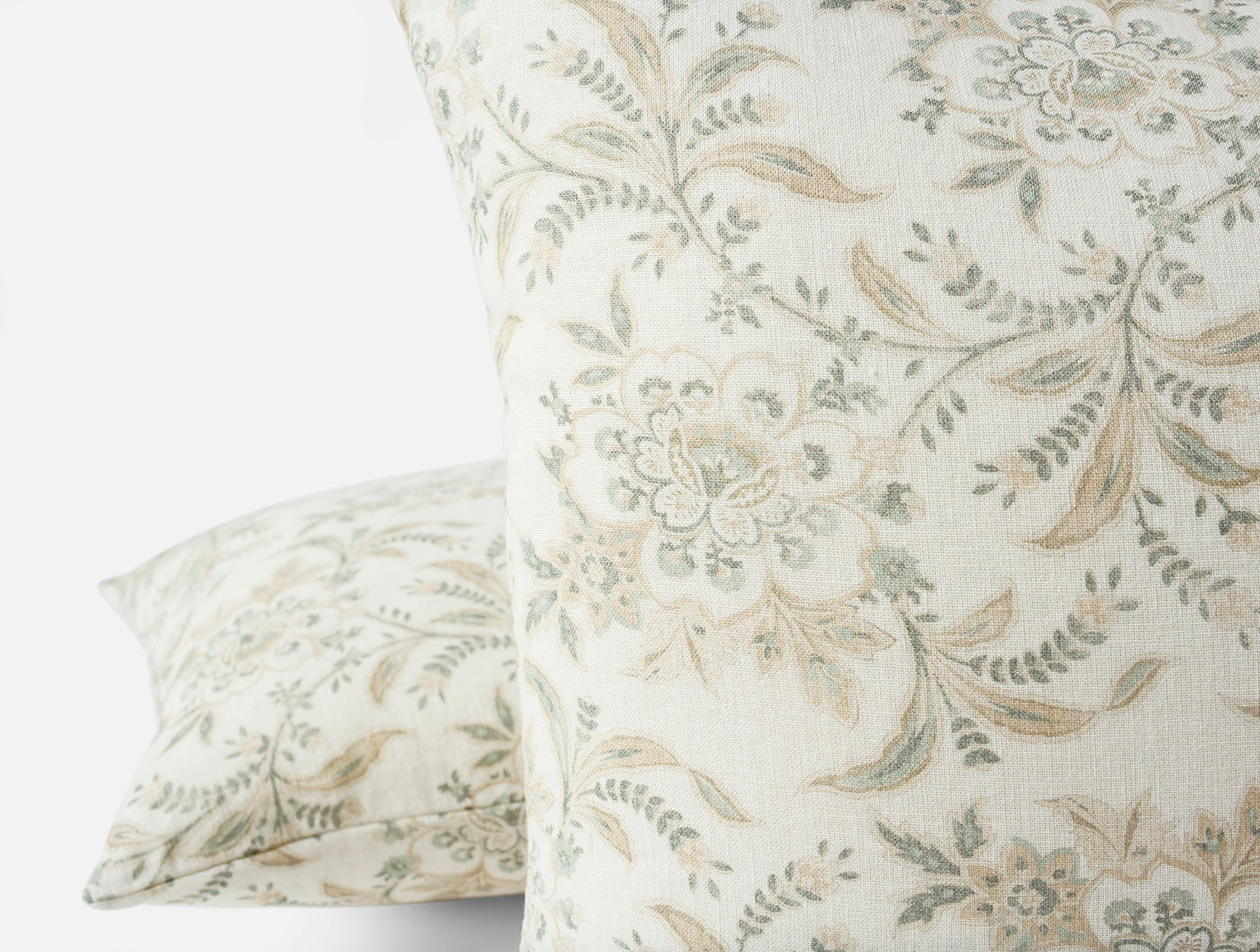 Close-up of Coyuchi Marguerite Print pillow covers showing sage floral and leaf pattern on ivory linen.