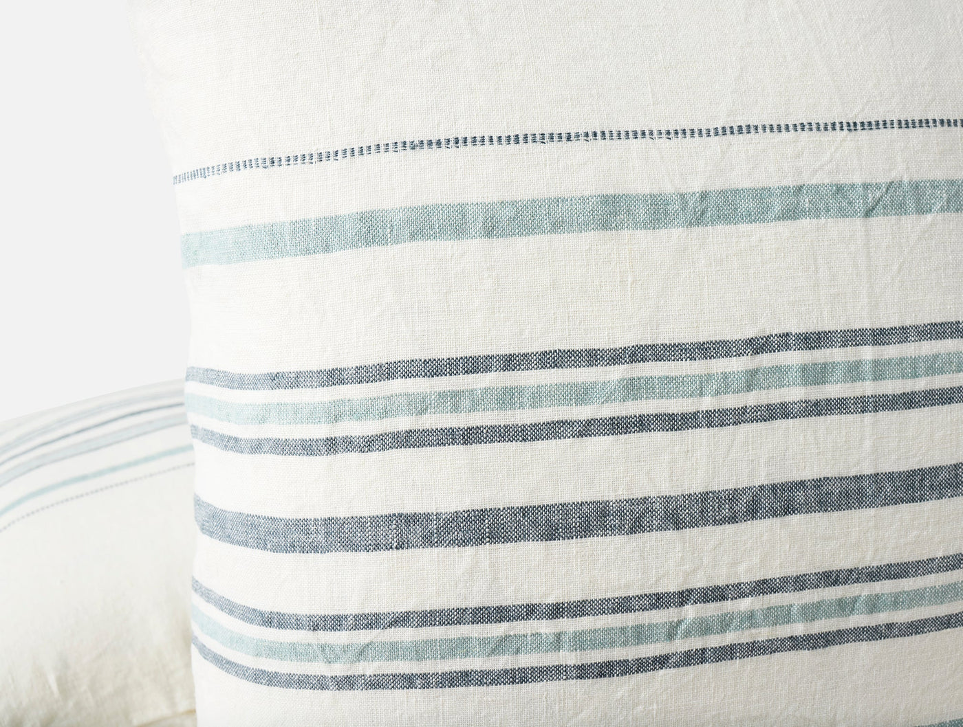 Close-up of Coyuchi Mojave linen pillow cover hem with teal and navy stripes.