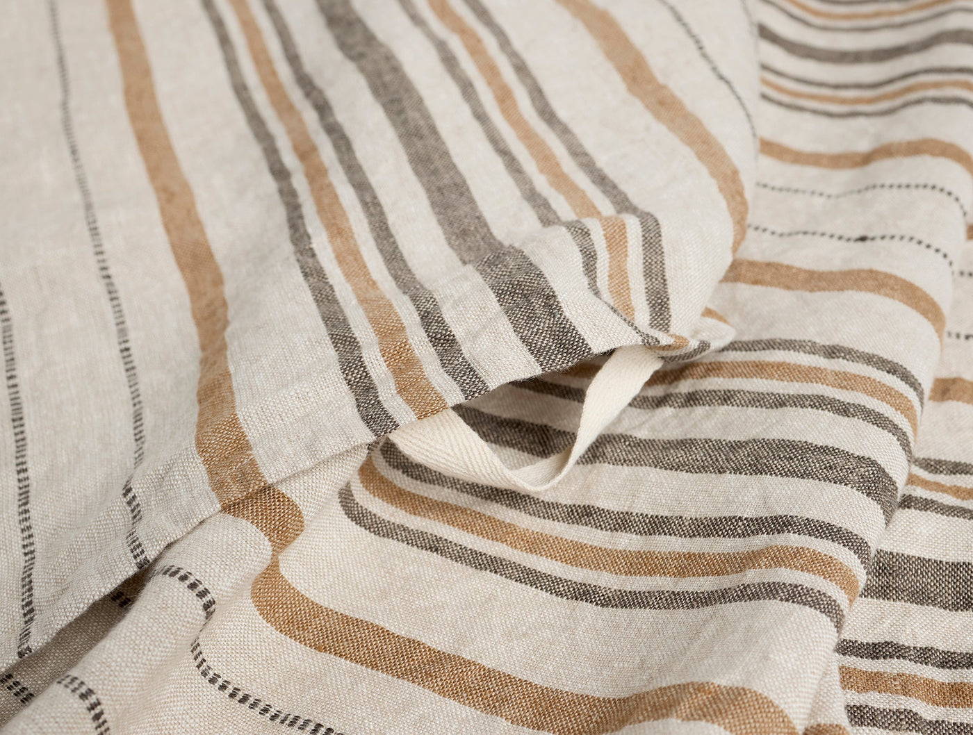 Close-up of Coyuchi Mojave linen hand towel showing tan and charcoal stripe weave detail.