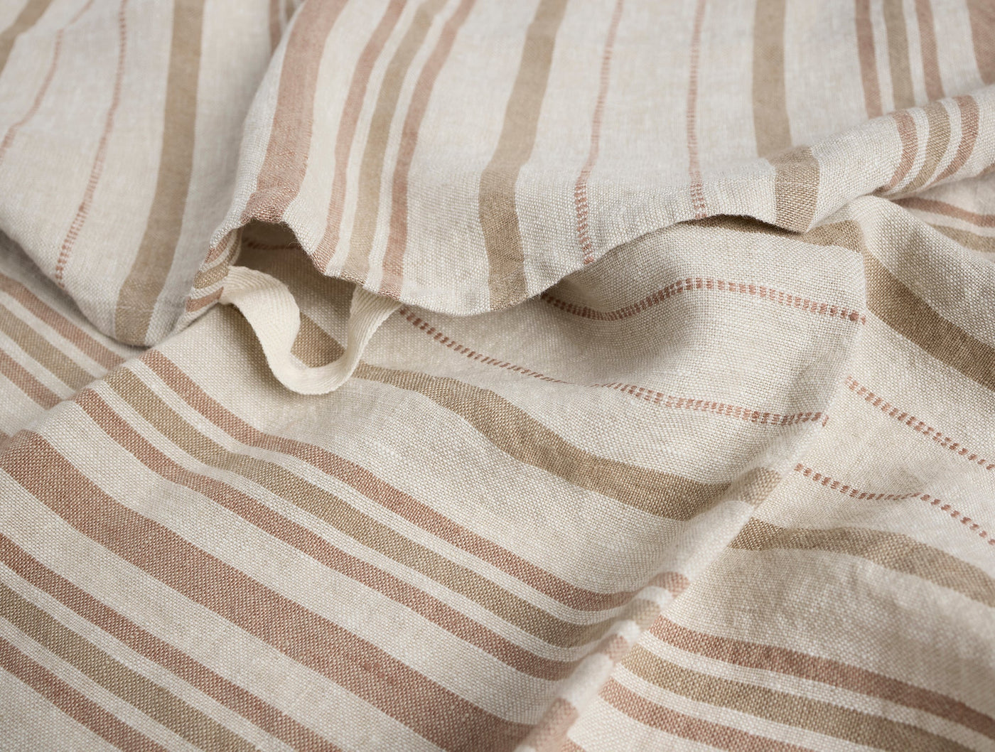 Close-up of Coyuchi Mojave linen hand towel, natural fabric with tan and rust woven stripes.