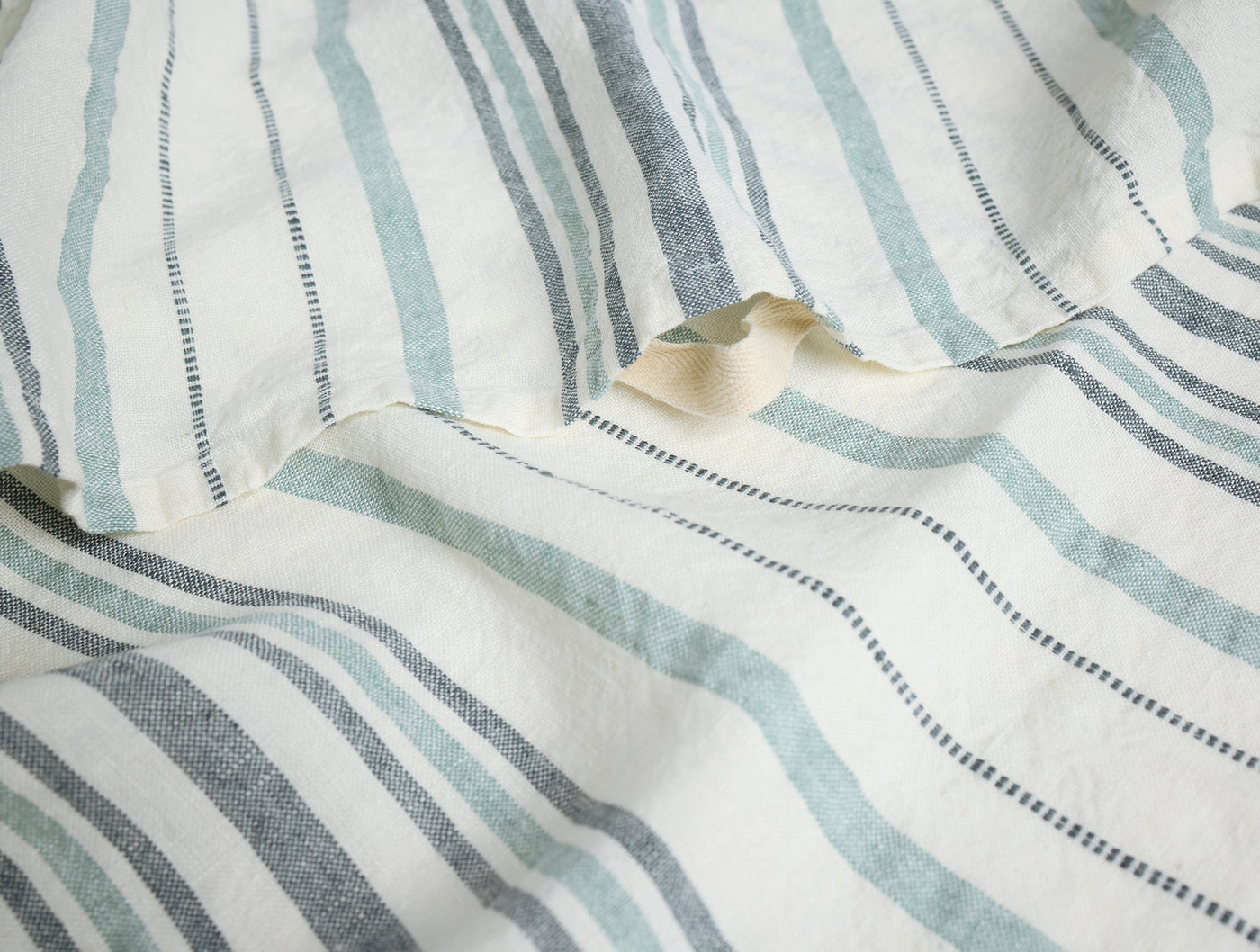 Close-up of Coyuchi Mojave linen hand towel showing sage and slate stripe weave detail.