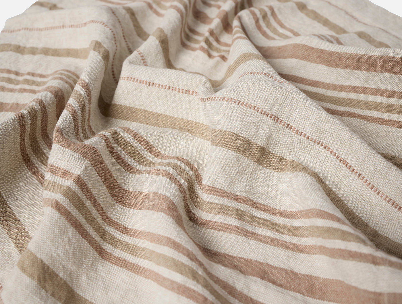 Close-up of draped natural linen with warm tan and terracotta stripes and hemstitch detail.