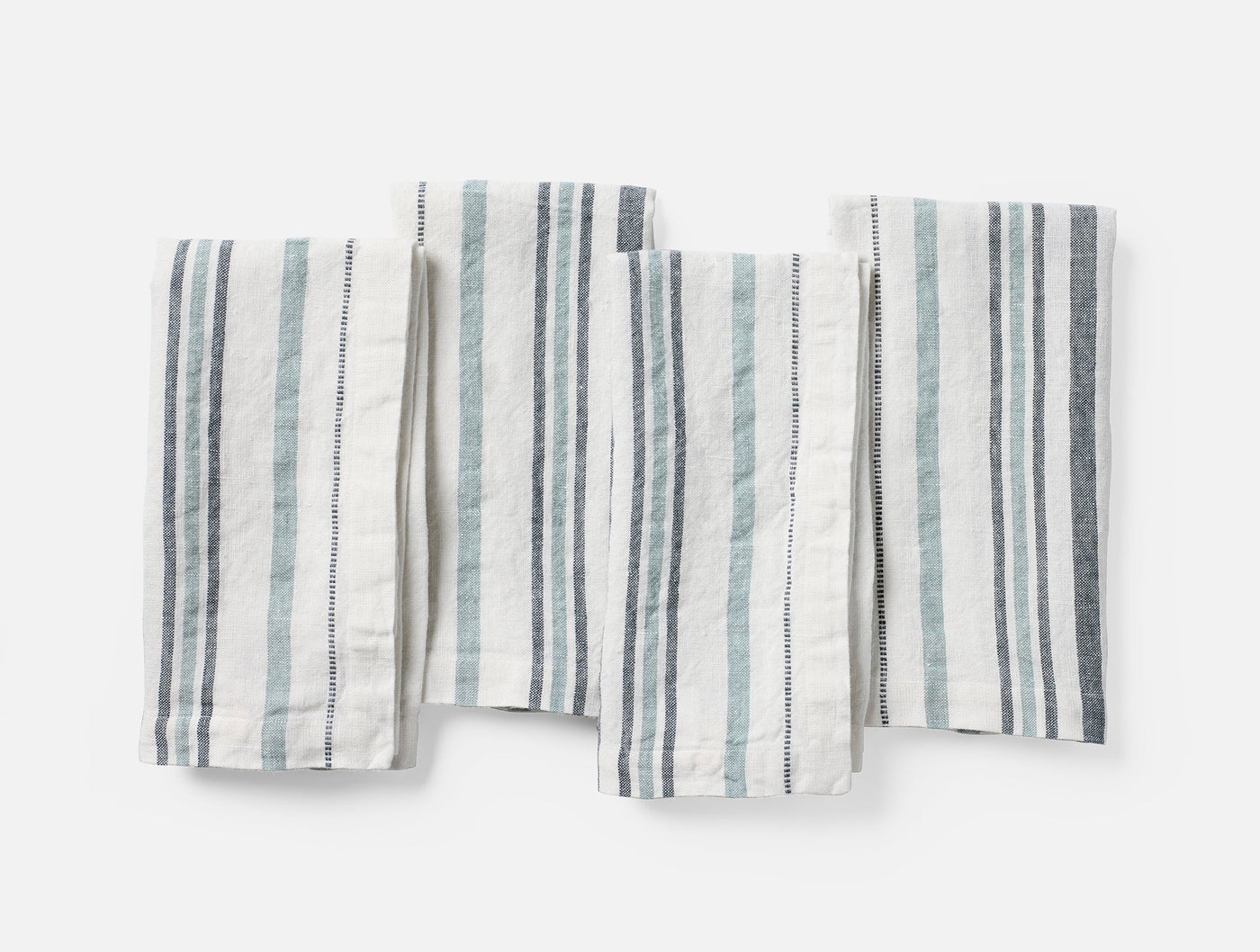 Four folded Coyuchi Mojave linen napkins in ivory with blue and grey stripes, flat lay view.