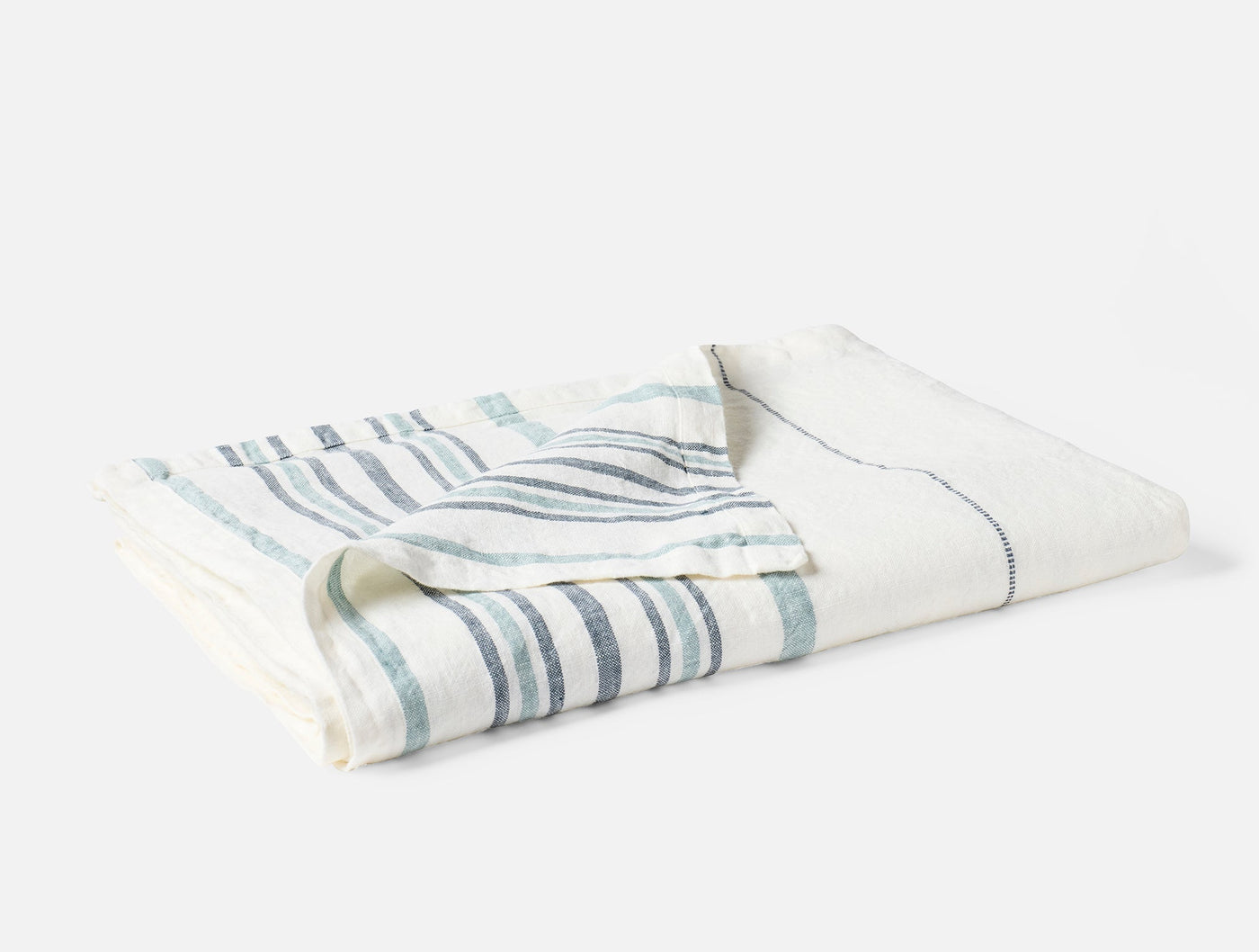 Folded ivory linen throw with varied-width slate and seafoam stripes, angled view.