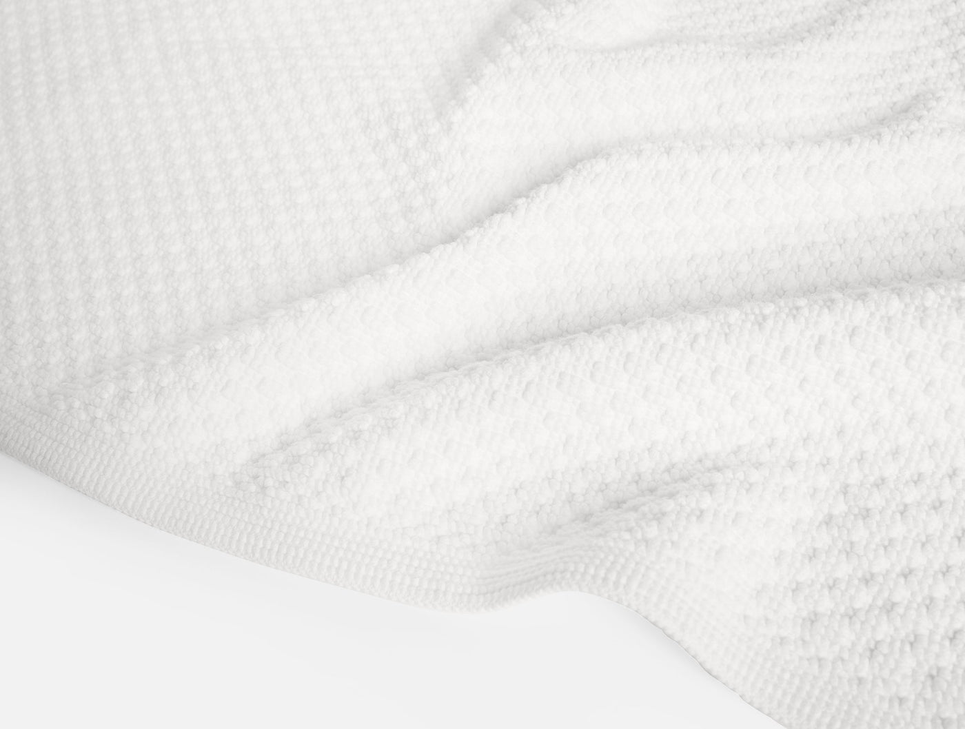Close-up of white Coyuchi Moonstone bath rug showing waffle-weave texture and terry loops.