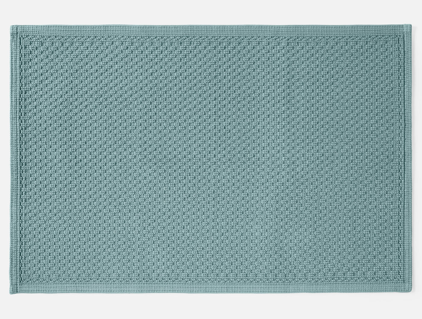 Coyuchi Moonstone bath rug in seafoam, overhead view showing waffle-weave texture.