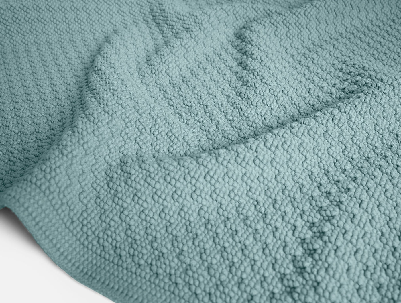 Close-up of Coyuchi Moonstone bath rug's nubby ocean blue cotton texture.