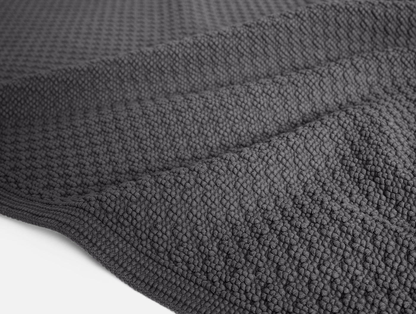 Close-up of Coyuchi Moonstone bath rug in charcoal, showing nubby cotton texture and border detail.