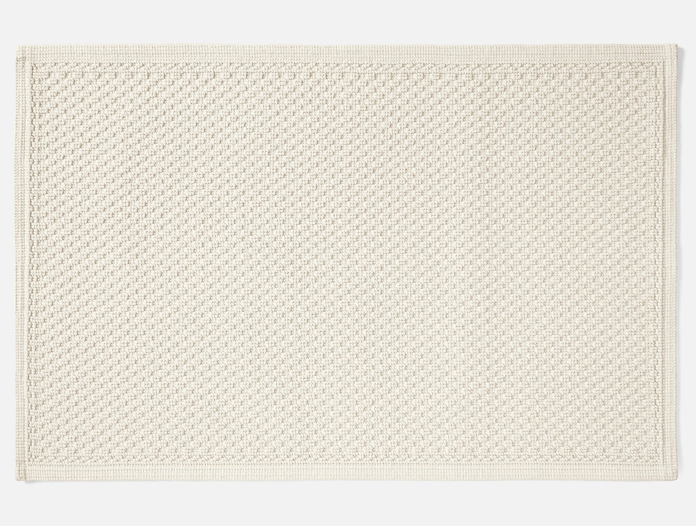 Coyuchi Moonstone bath rug in ivory, overhead flat lay showing woven texture and border detail.