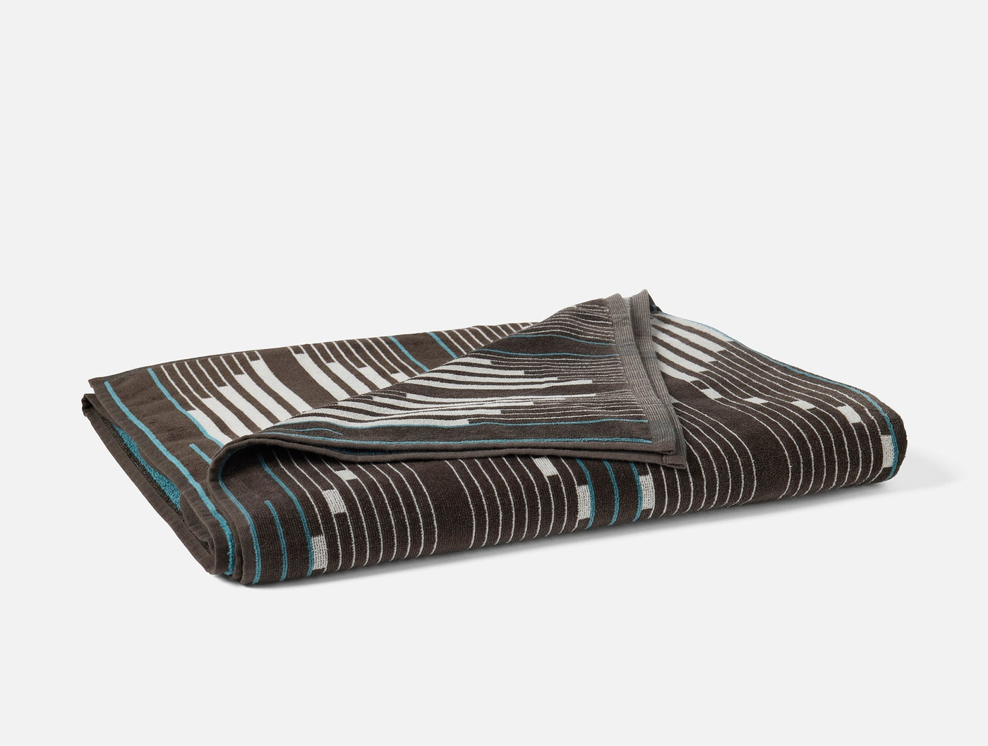 Folded Coyuchi Morelia beach towel in charcoal with white stripe and teal edge detail.
