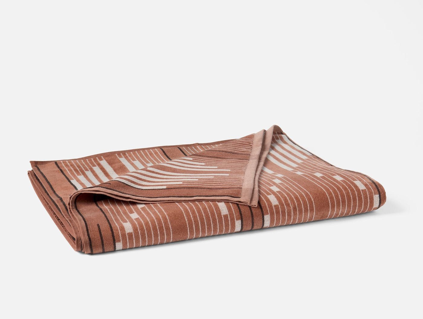 Folded terracotta Morelia beach towel showing geometric stripe pattern on reverse side.