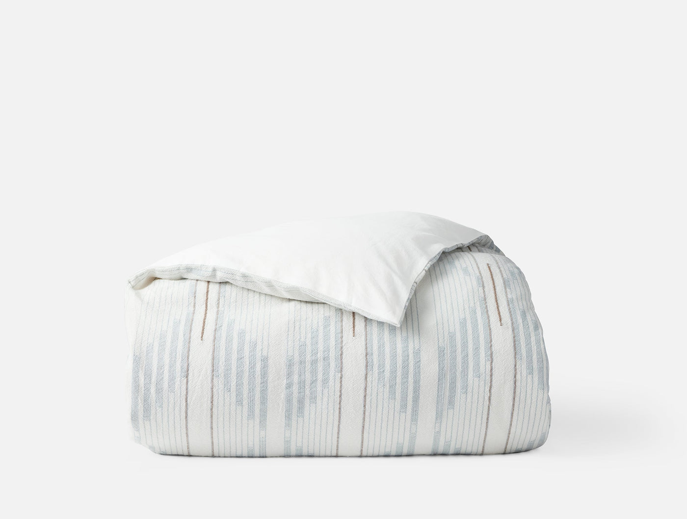 Coyuchi Morelia duvet cover folded, showing pale blue ikat stripe pattern against white background.