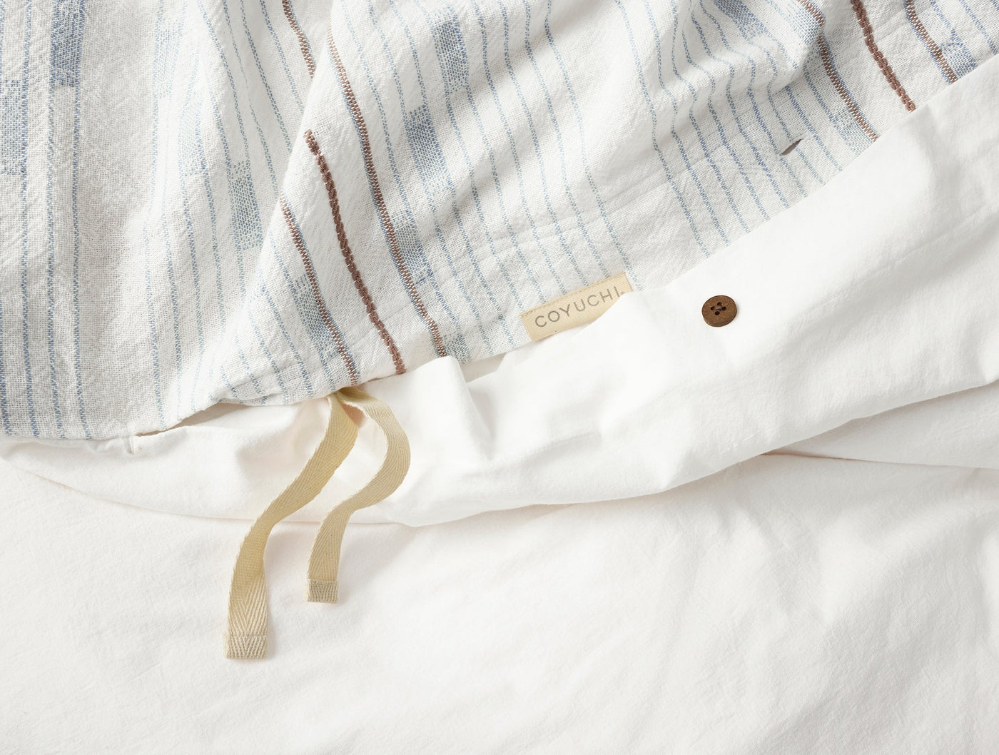 Close-up of Coyuchi Morelia duvet cover closure with button and ivory linen ties.