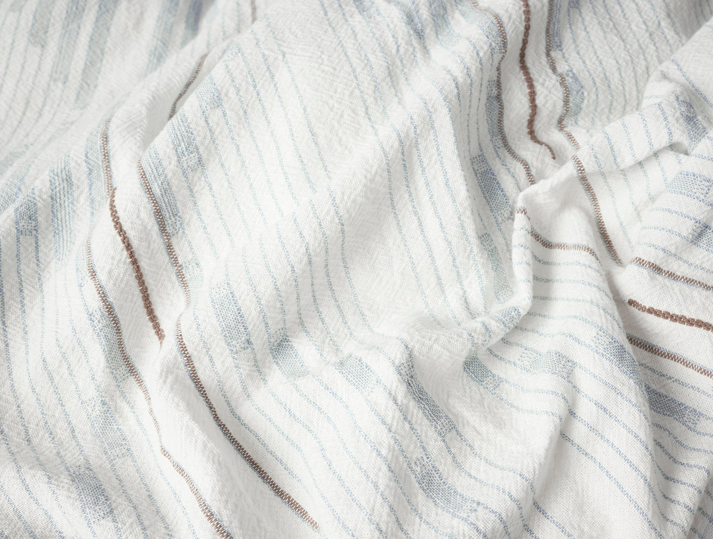 Close-up of ivory woven fabric with pale blue and brown stripe detail.