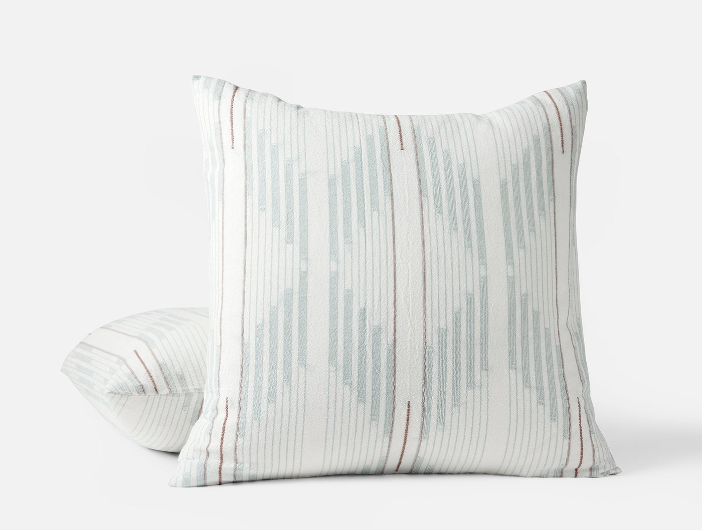 Close-up of Coyuchi Morelia sham showing teal ikat stripes and terracotta pinstripes on white.