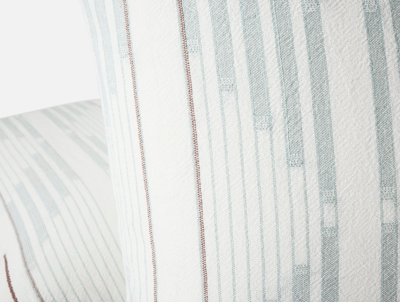 Close-up of Coyuchi Morelia sham showing sage stripe weave and copper accent stitching detail.