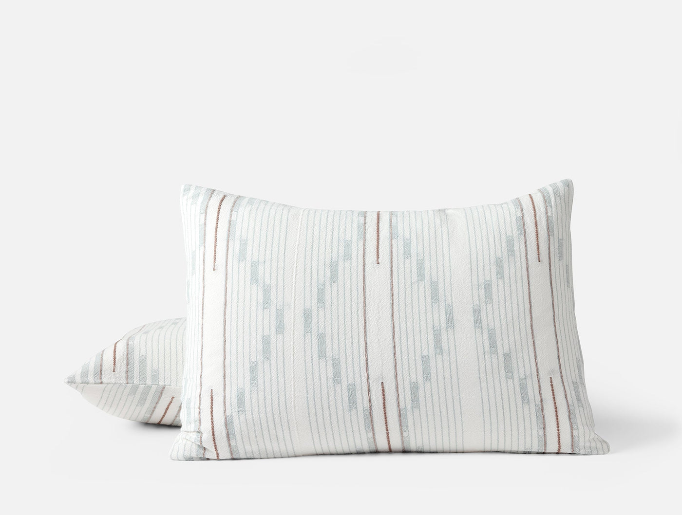 Close-up of two Morelia shams stacked, showing pale blue and rust ikat stripe pattern.