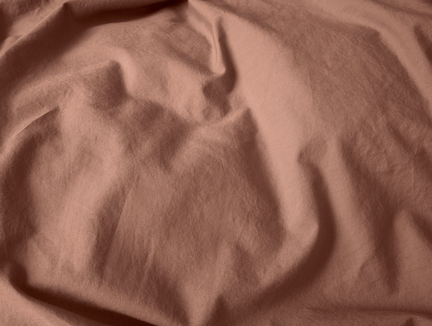 Close-up of terracotta crinkled percale fabric with natural drape and texture.