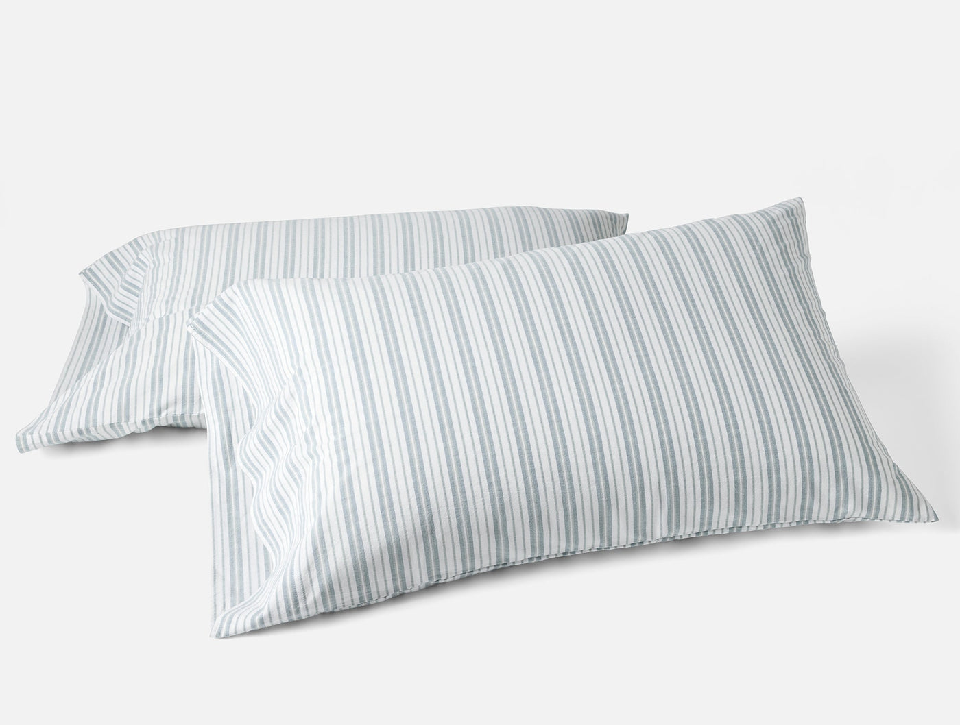 Two Coyuchi Crinkled Percale pillowcases in soft blue-grey ticking stripes on white.