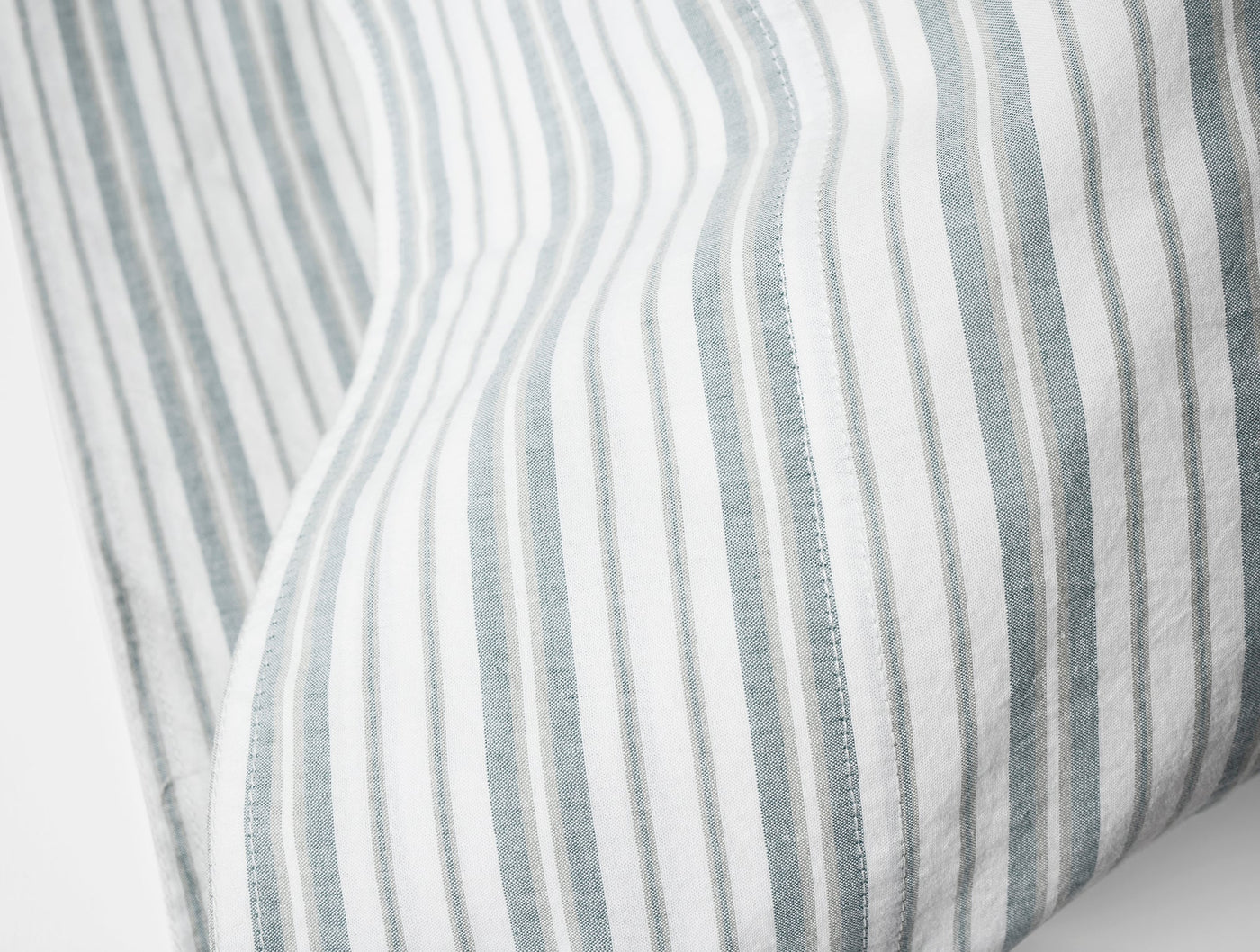 Close-up of slate blue pinstripe on white crinkled percale pillowcase edge and hem.