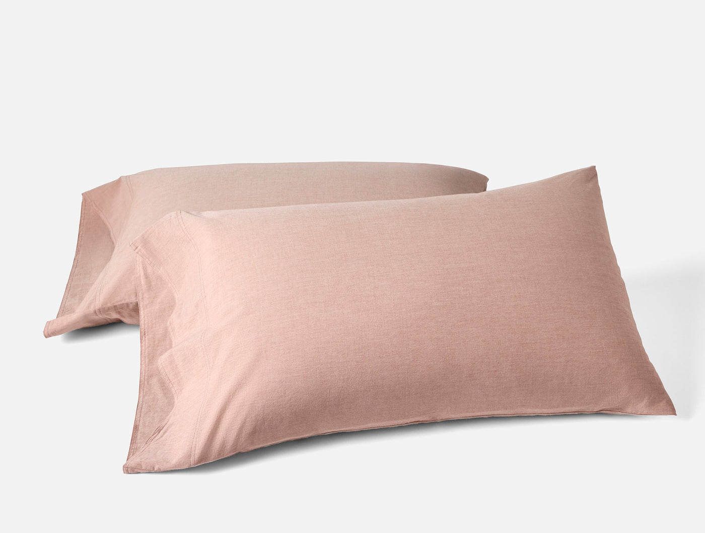 Two blush pink Coyuchi Crinkled Percale pillowcases stacked at an angle on white background.