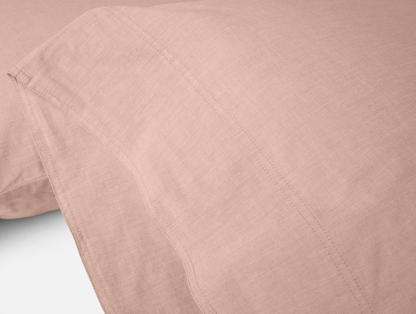 Close-up of blush Coyuchi Crinkled Percale pillowcase hem detail showing texture.