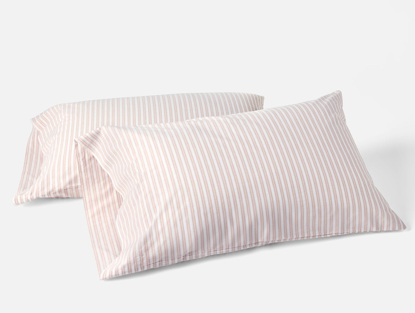 Two Coyuchi Crinkled Percale pillowcases in blush pink pinstripe on white.