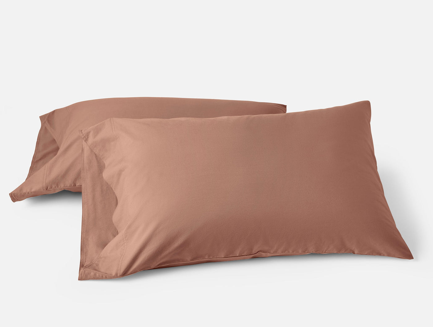 Two Coyuchi Crinkled Percale pillowcases in terracotta, stacked on a white background.