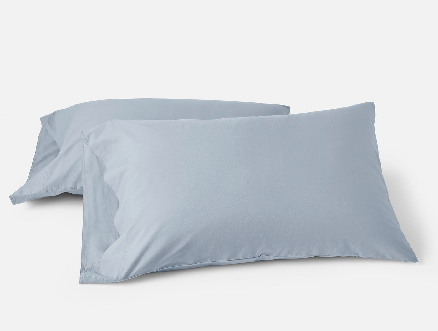 Two mist blue Coyuchi Crinkled Percale pillowcases, overlapping on white background.