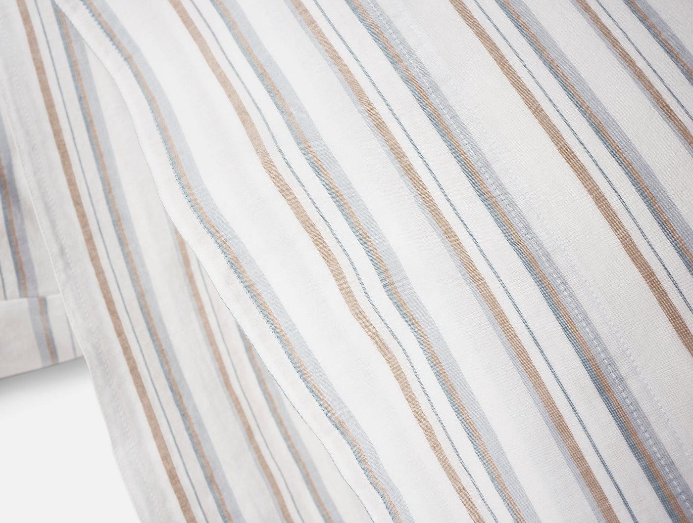 Close-up of Coyuchi Crinkled Percale pillowcase showing tan, gray, and blue stripes.