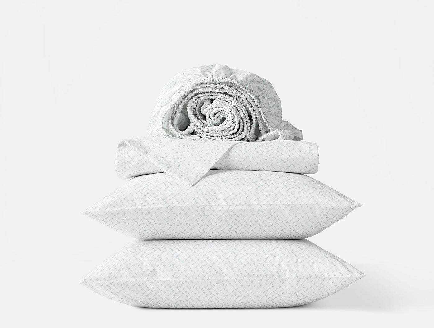 Stacked white Coyuchi Print Percale sheet set with rolled fitted sheet on top.